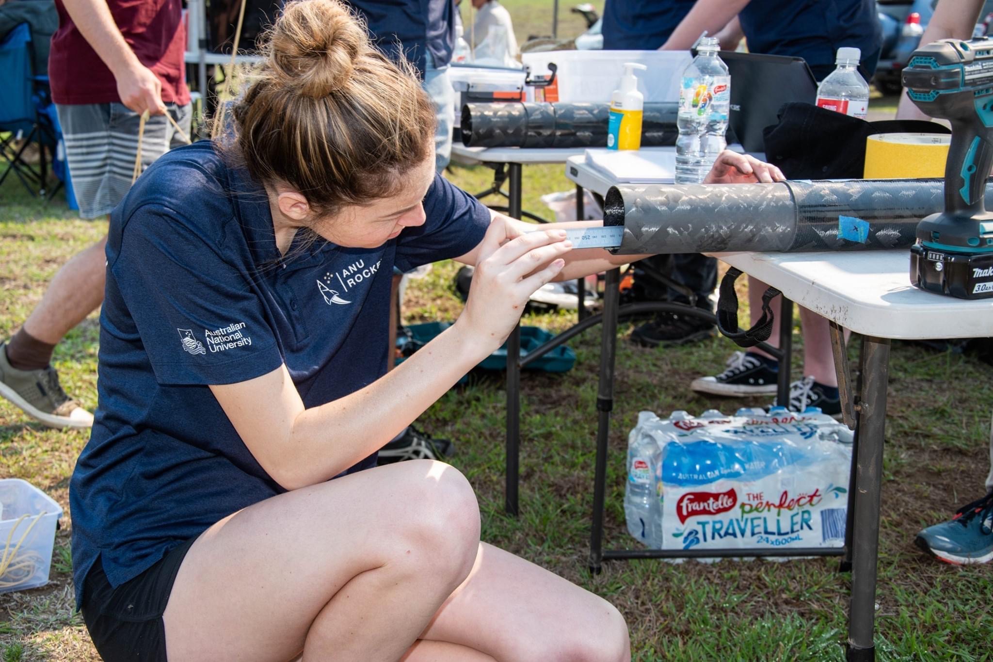 Photograph featuring ANU Student, a Bachelor of Engineering (Honours) student, posing with a rocket
